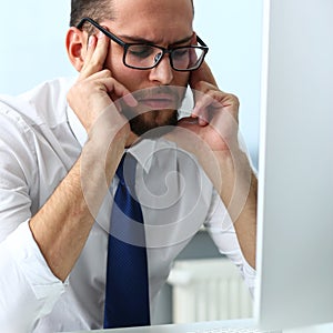 Tired clerk at laptop pc workplace wearing glasses