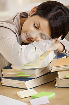 Tired college student sleeping on pile of books