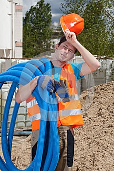 Tired construction worker holding pipes
