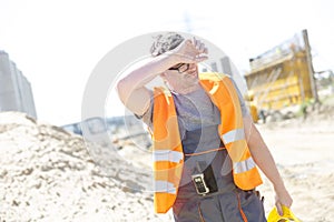 Tired construction worker wiping forehead at site