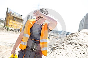 Tired construction worker wiping forehead at site