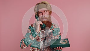 Tired crazy hippie man talking on wired vintage retro telephone of 80s, fooling making silly faces