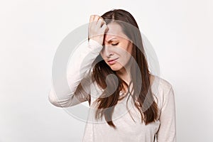 Tired crying disconcerted young woman in light clothes keeping eyes closed, putting hands on head isolated on white