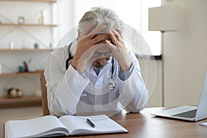 Tired depressed male doctor feels desperate thinking of problem photo