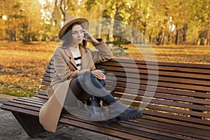 Tired or depressed young woman touching her head in autumn park. The girl