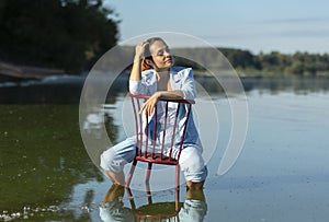 Tired digital nomad, female business entrepreneur sits in chair in water, blue sky is on