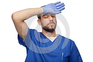 tired doctor or male nurse in blue uniform