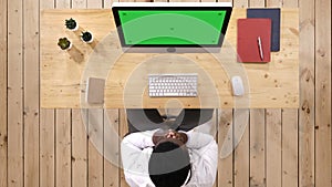 Tired doctor sitting in front of monitor at his deck at medical office. White Display.