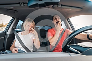 Tired and drowsy driver man yawns while next to sleeping exhausted wife. Driving car at high speed on road. Risk and hazard of