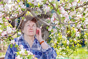 Tired elderly woman at the dacha talking on a cell phone