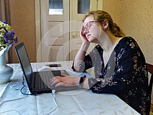 Tired european young woman work on laptop at home