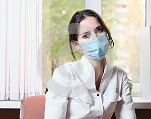 tired exausted asian woman doctor in a clinic. hospital rest room. woman wearing medical uniform and face protective photo