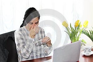 Tired executive woman in front of her laptop, at work.