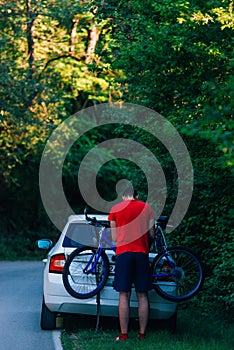 Tired exhausted biker puts his bike on a car to get a ride