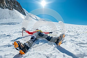 Tired exhausted climber lying under Mont Blanc du Tacul mountain. Wide opened legs in boots with crampons and mountaineering