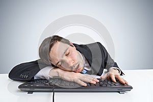 Tired or exhausted overworked businessman is sleeping on keyboard