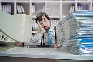 Tired exhausted overworked man with many documents on desk. Overwork and paperwork concept.