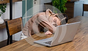 Tired exhausted sleepy Asian young female businesswoman freelancer sitting napping sleeping on table resting relaxing from home