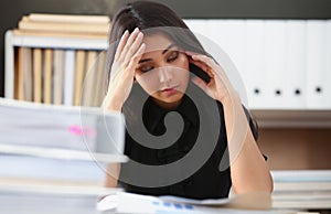 Tired and exhausted woman looks at documents propping up her head with her hands