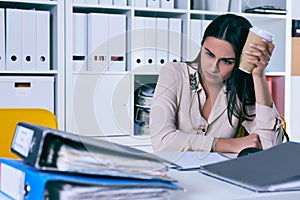 Tired and exhausted woman looks at the mountain of documents. Deadlines for the submission of reports.