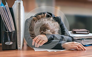 Tired and exhausted workaholic woman sleeping on desk in office photo