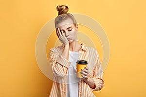Tired fair-haired sleepy woman holds a cup of coffee