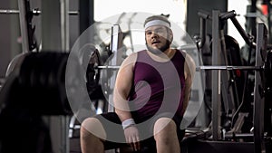 Tired fat man having rest after workout exercise, strength of muscles, training