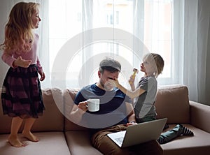 Tired father with his two kids during quarantine. Stay at home concept. Online working and household at the same time while