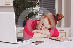 Tired fatigue ginger female student works all night at course paper, falls asleep directly at working place, surrounded with moder