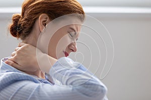 Tired fatigued business woman feeling hurt rubbing stiff neck photo