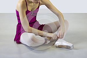Tired female dancer  unfasten laces of pointe shoes