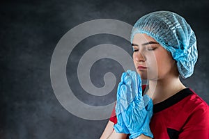 Tired female doctor with head in hands sad and praying after surgery isolated on black