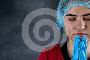 Tired female doctor with head in hands sad and praying after surgery isolated on black