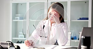 Tired female doctor takes off glasses at workplace in clinic