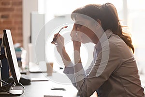 Tired female employee suffer from headache at workplace