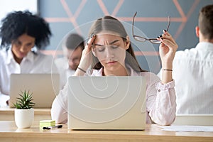 Tired female employee suffering from headache at workplace