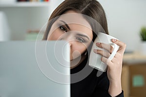 Tired female employee at workplace in office holding cup of tea