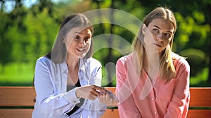 Tired female listening to annoying friend sitting outdoors, envy, selfishness