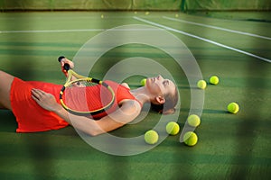 Tired female tennis player lies on court