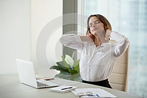 Tired female worker stretching in chair relaxing after working d