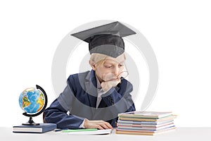 Tired first grader boy in students hat does his homework. Bored schoolboy isolated on white background. Education concept