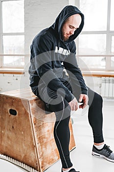 Tired fit man wearing hoodie relaxing after hard training box at light hall