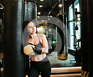 Tired fit woman resting after training near heavy bag