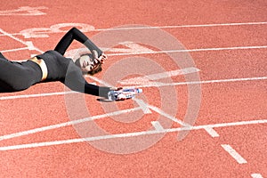 Tired fit woman in sportswear resting after workout or running, holding a bottle of water, taking a break during training