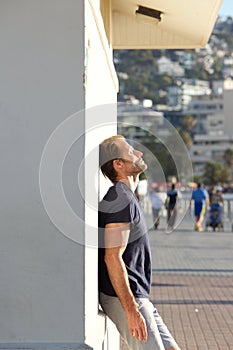 Tired fitness man leaning against wall