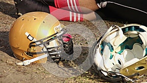 Tired football player sitting on the ground and relaxing after difficult game