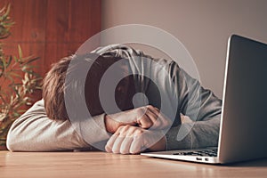 Tired freelance worker asleep at home office desk