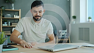 Tired freelancer Arab man working with laptop in apartment then leaving quitting