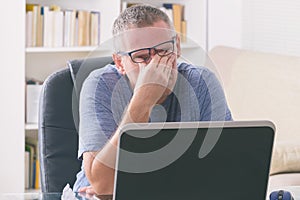 Tired freelancer man rubbing his eye