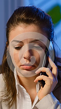 Tired freelancer woman having conversation on phone while working